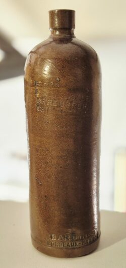 bouteille en grès vernissé qui a été utilisée pour l'exportation d'alcool vers les États-Unis pendant la prohibition. Cette dame-jeanne en céramique de couleur marron mesure environ 30 cm de hauteur. Elle est en très bon état. La bouteille porte l'inscription "Bardinet Bordeaux-France" estampillé à la base et l'inscription "Federal-law forbids, sale or reuse of this bottle"